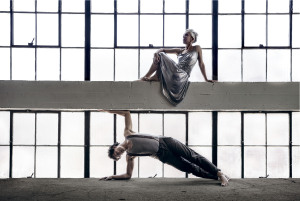 Woman in silver dress over concrete block man under in an extended pose