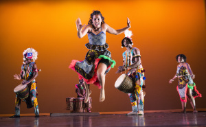dancer jumps in front of drum ensemble