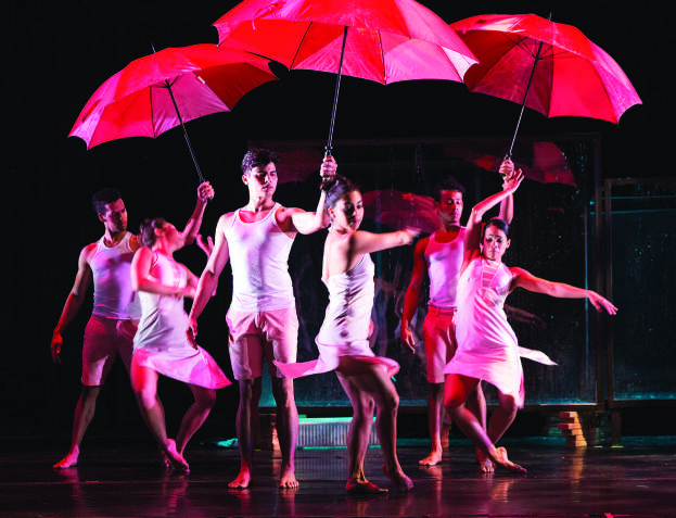 dancers turn and stand with red umbrellas