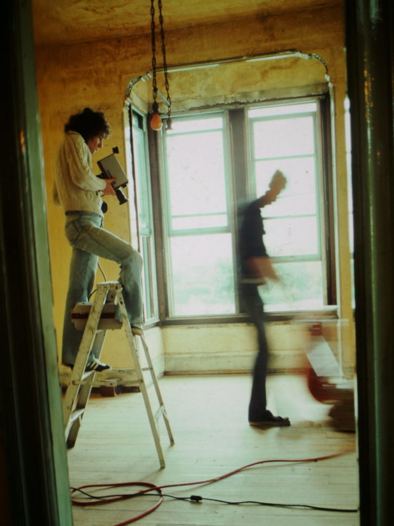 man on ladder films artist sanding floor