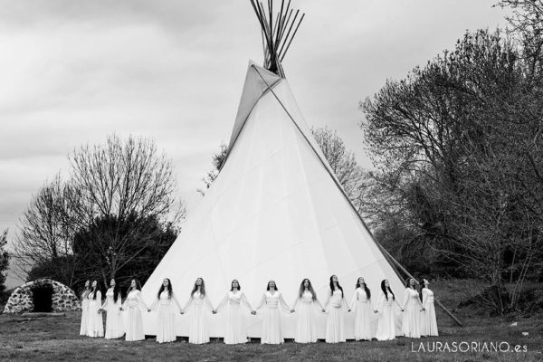 women stand around teepee holding hands