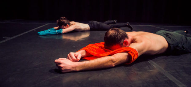two dancers lie face down removing tshirts