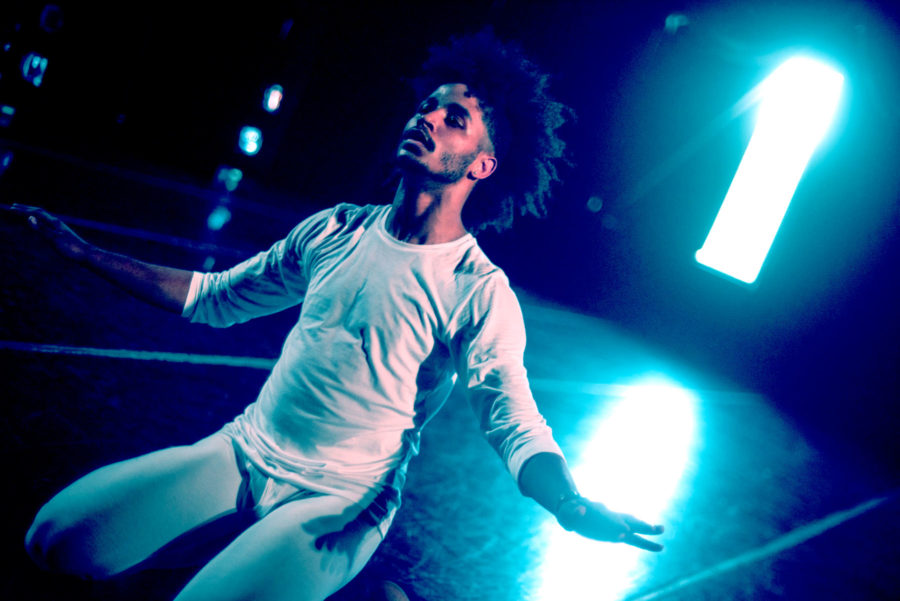 dancer kneels in blue light on stage