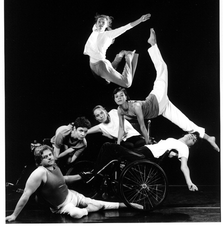 Six dancers, four jump and lean on two in wheelchairs