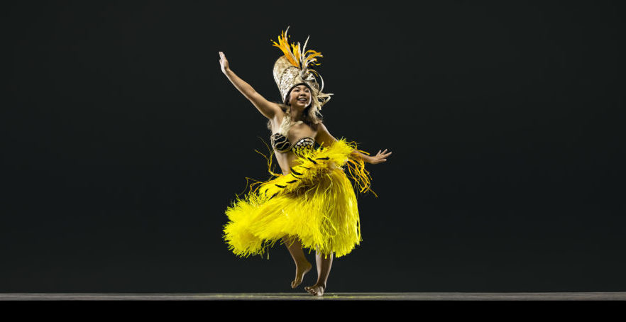 Dancer in yellow skirt stretches arms diagonally