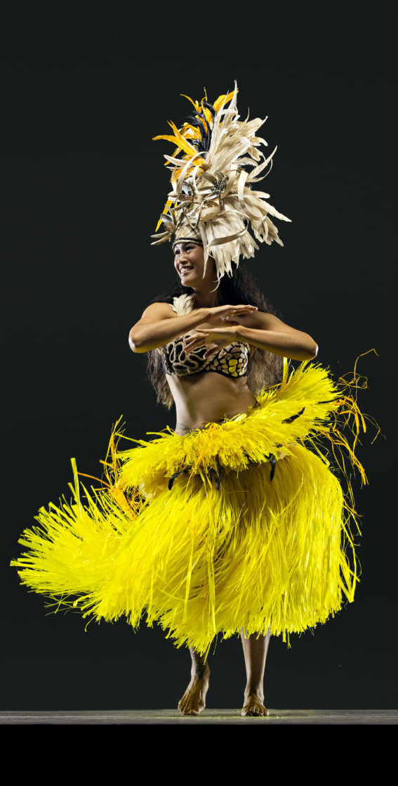 dancer in yellow skirt looks to right with arms crossed