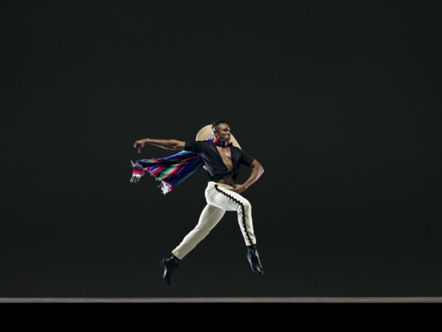 Male dancer leaps with hat and cape