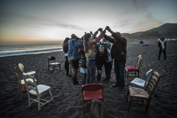 group huddles in center of chair circle on beach