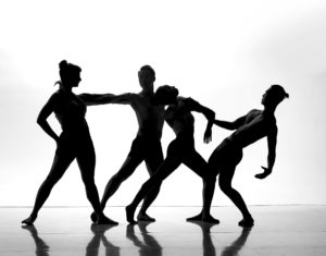 Silhuette of 4 dancers against white background.