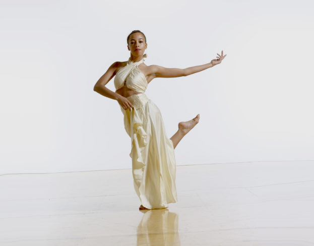 Dancer in white tunic, arm and leg lifted