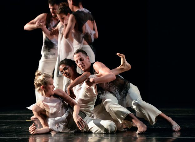 Two groups of three dancers holding each other.