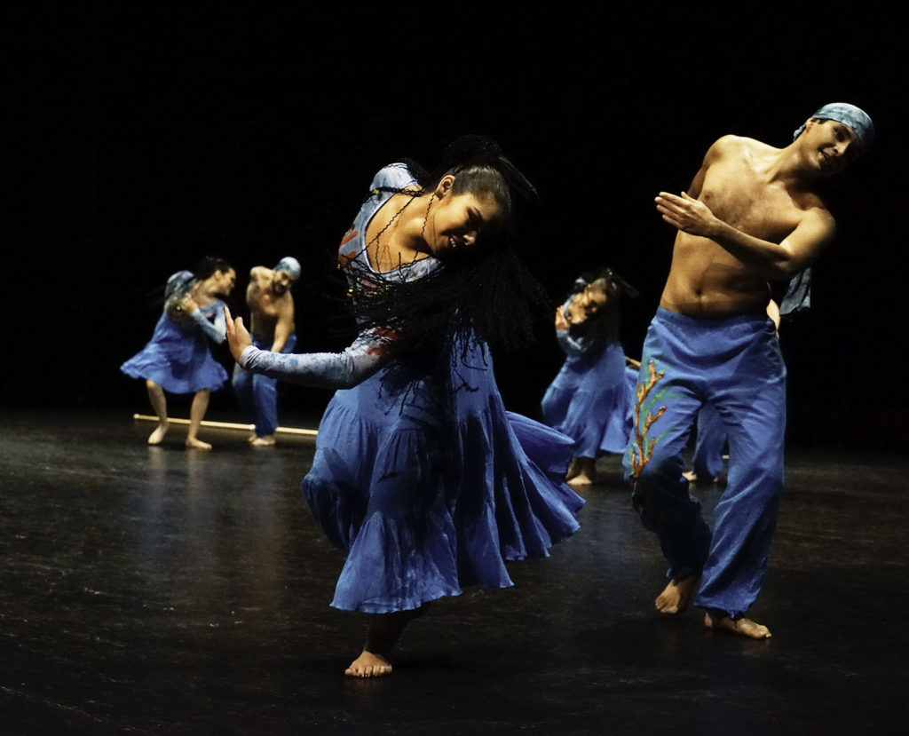 Group of performers in blue bending at the waist