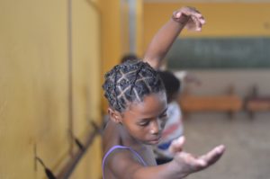 Young girl performing port de bra in a classroom