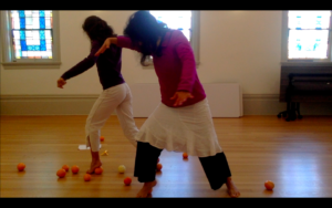 Two dancers squishing oranges
