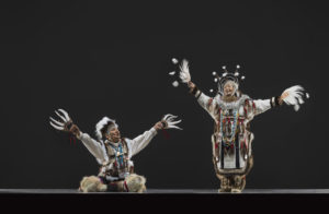 two Eskimo dancers, one standing, one seated
