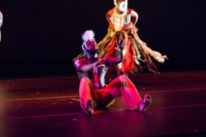one male dancer on the floor wearing red dance pants