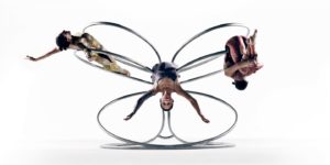 3 dancers draped over a large metal circular prop