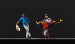 two ballet folklorico dancers, one male with a straw hat and tied scarf, one female with a flower headdress