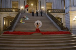 woman in a red backless gown on the grand staircase dancing with a parasol