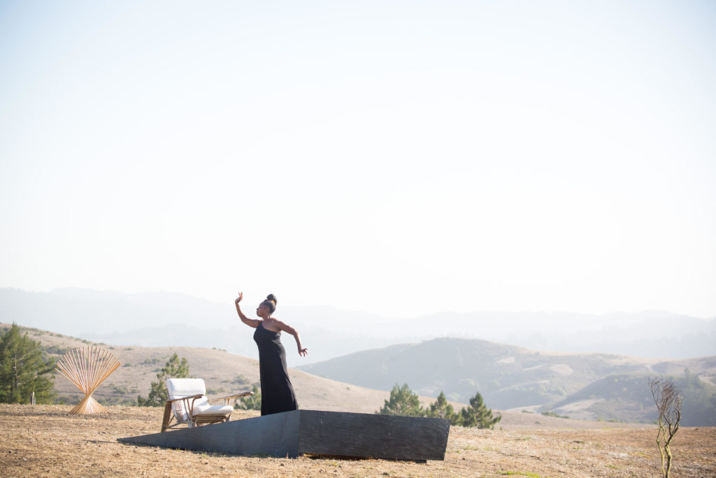 Woman holding greek pose on platform in field