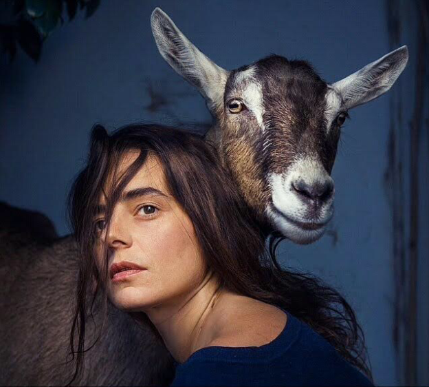 A woman beside a goat.