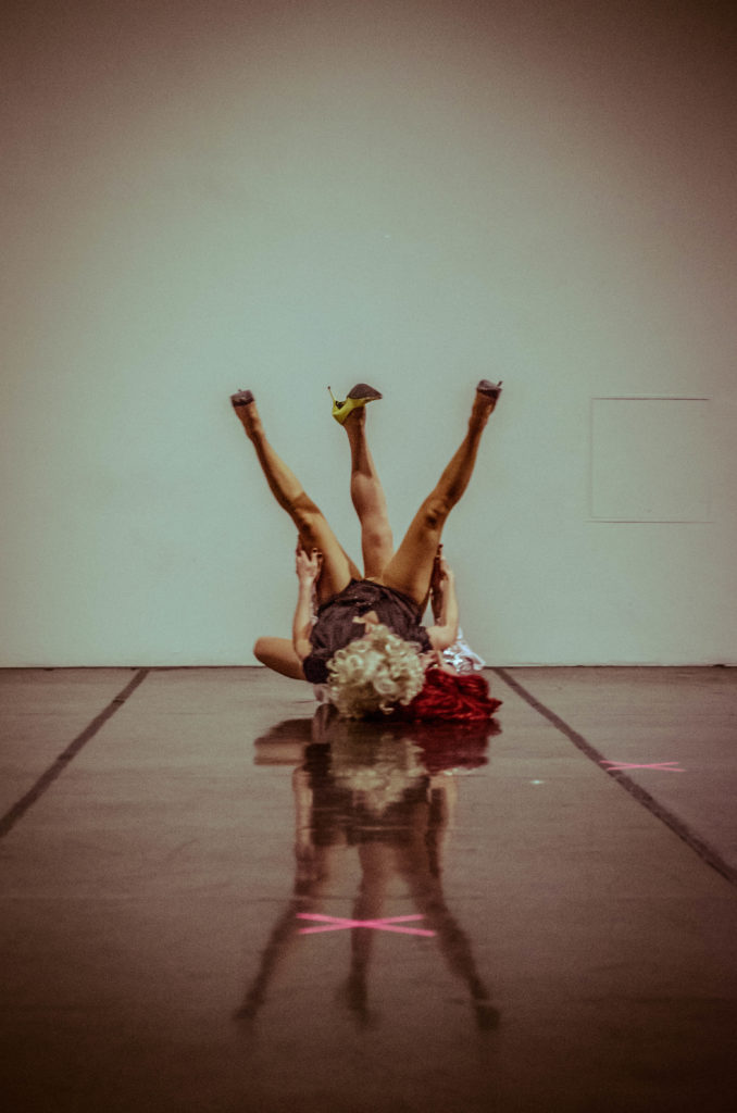 Two dancers on the ground with legs in the air. 