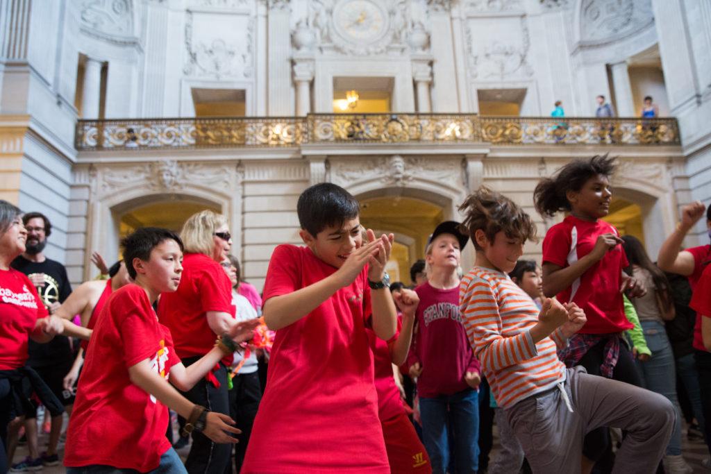 A large group of people dancing at San Francisco City Hall.