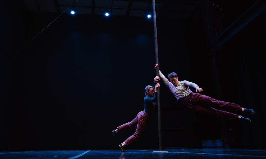 Two people swinging on a rope hanging from the ceiling.