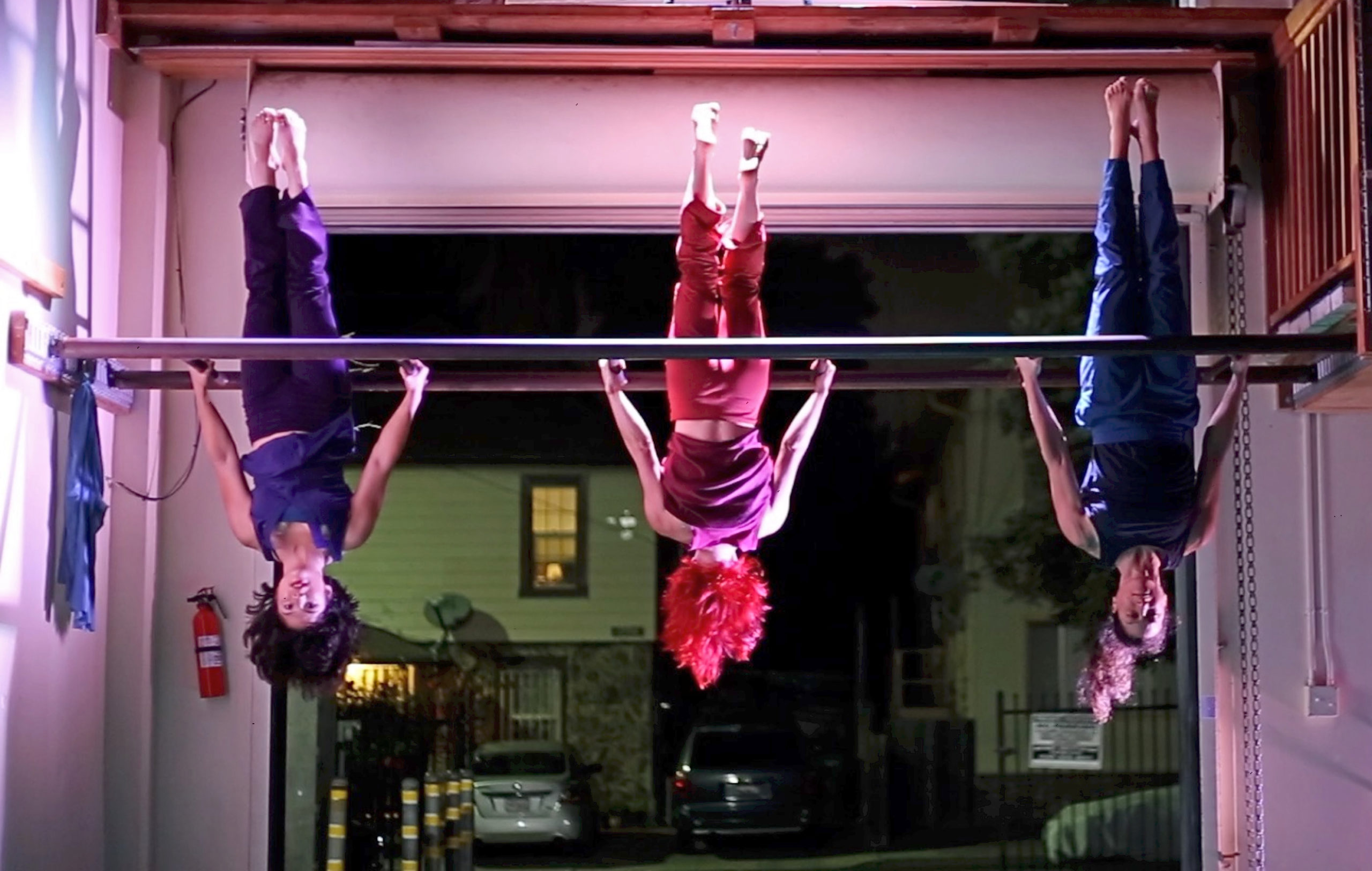 3 dancers hanging from a pole inside a studio