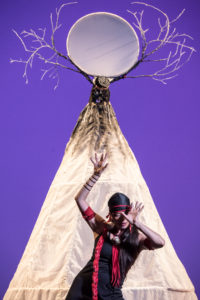 Solo female dancer onstage in front of a Native American tepee 
