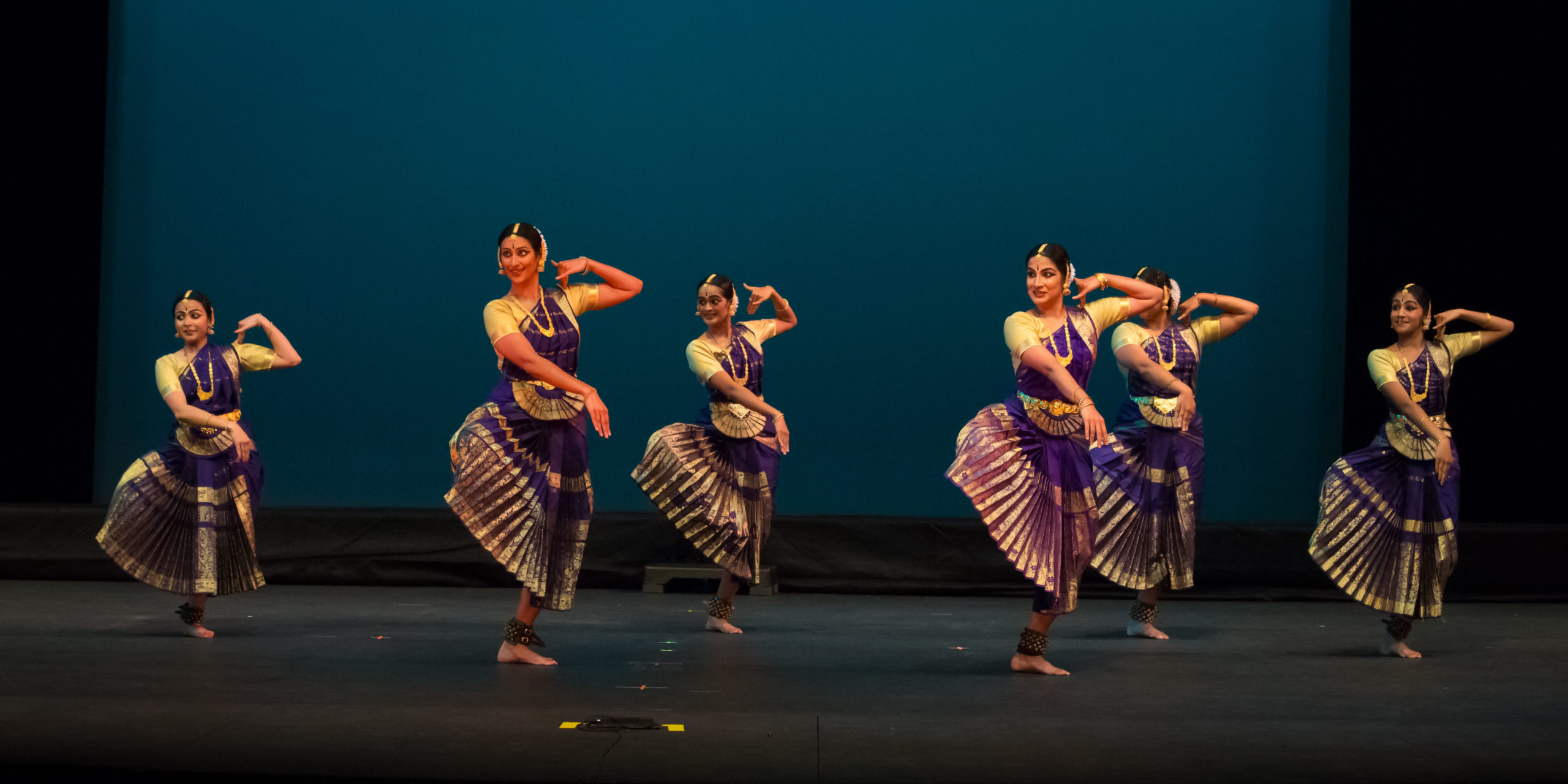 Group of female Indian dancers mid-movement on stage