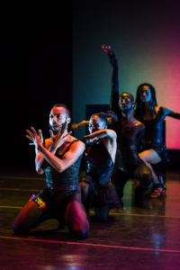 Performance photo of KnowShade Vogue dancers sitting in a column formation