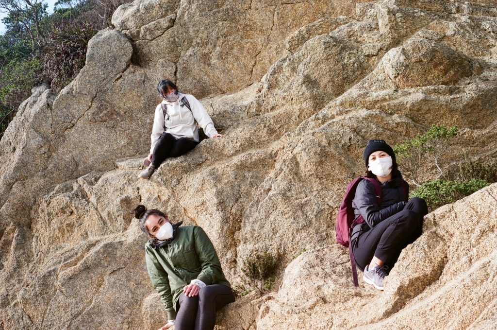 Trio of women outside sitting on a mountainside