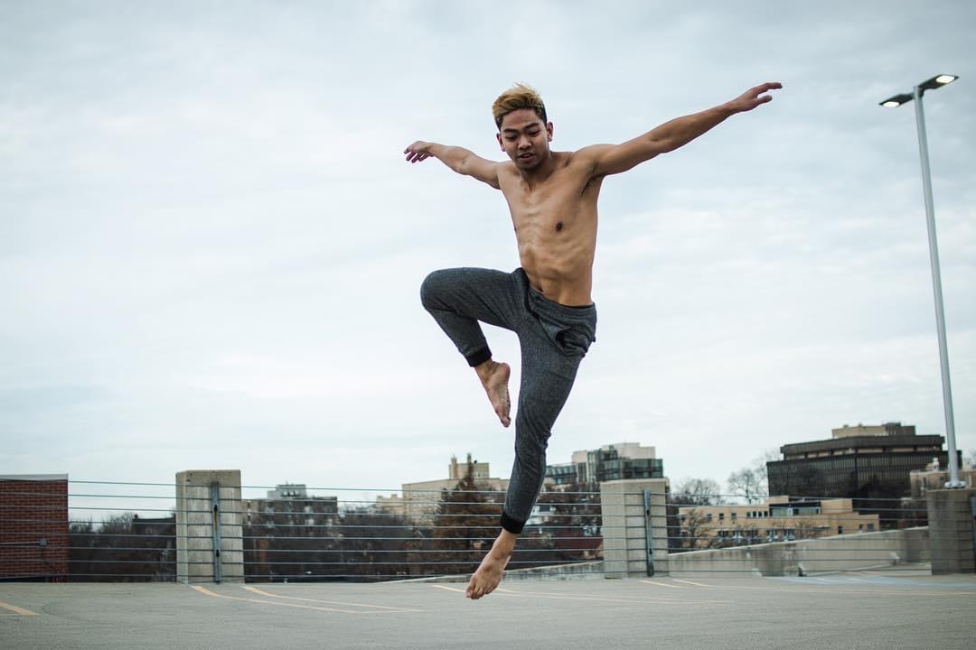 A male dancer jumping in the air in an empty parking lot