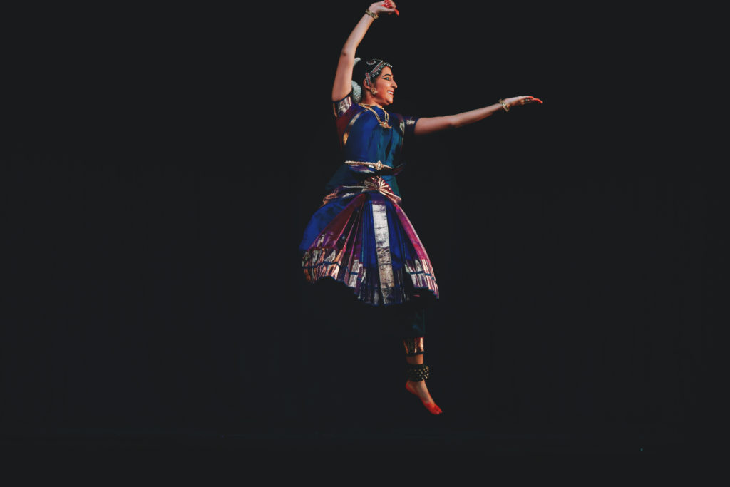Performance photo of Preethi Ramaprasad, a Bharatanatyam dancer, in mid-leap