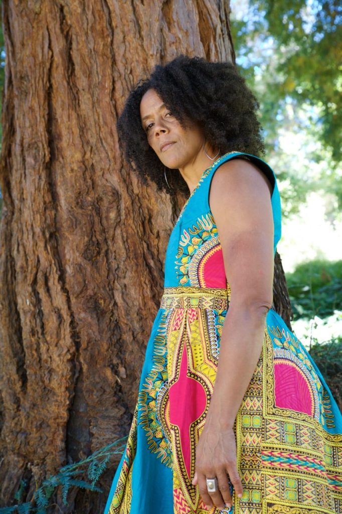 A headshot of amara tabor-smith standing next to a tree.