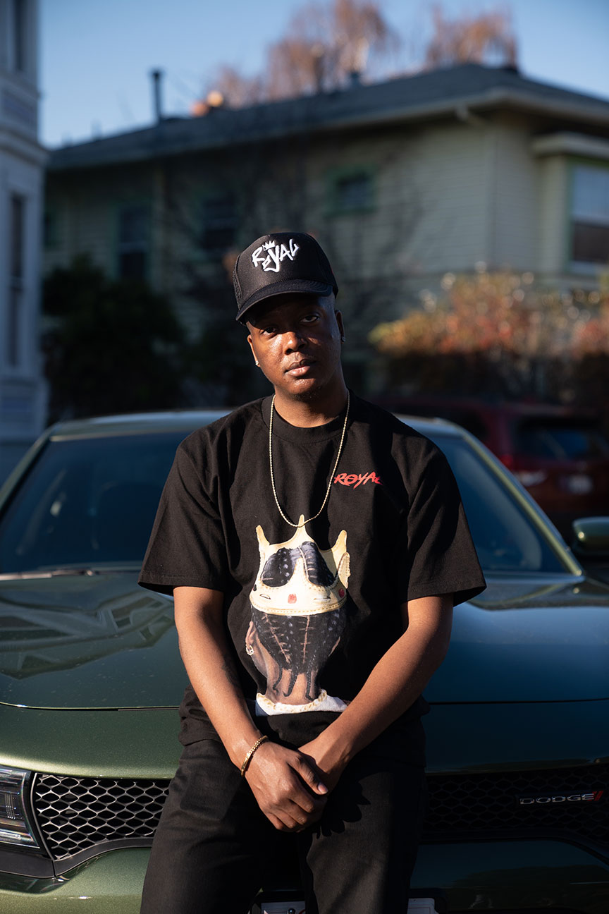 Tarik, male, African-American, wearing Royal Supply clothing brand, Dodge Challenger, neighborhood background.