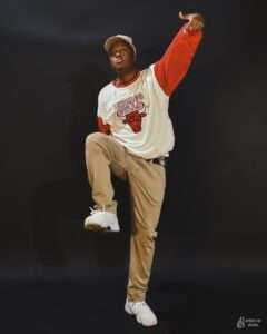 Tarik, male, African-American, wearing Chicago Bulls red and white, in Krump pose, white Jordan 11s, dark background