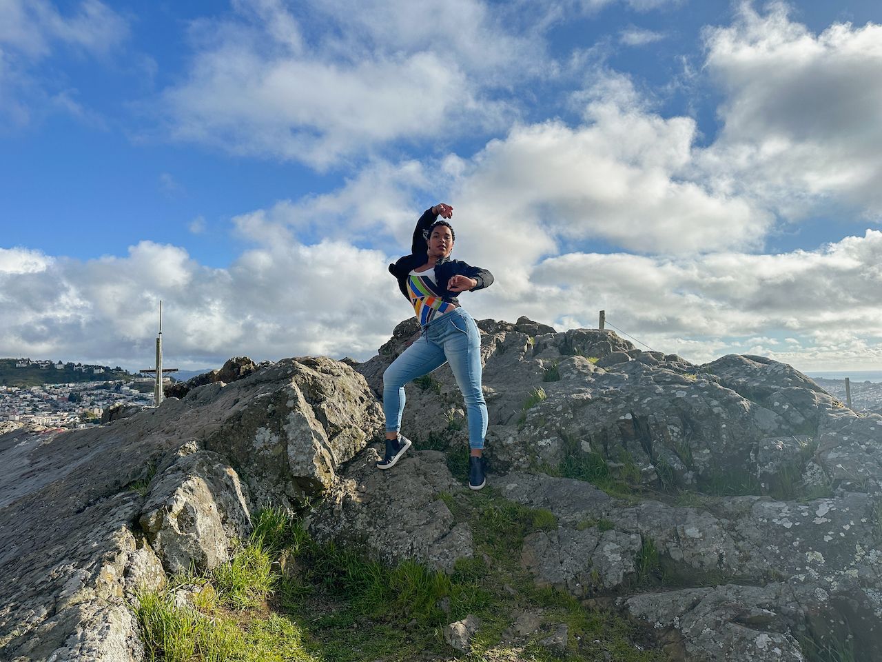 A female dancer dressed poses confidently on a rocky hill.