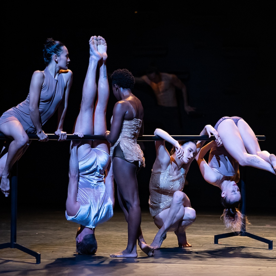 Five dancers move over a bar against a black background.