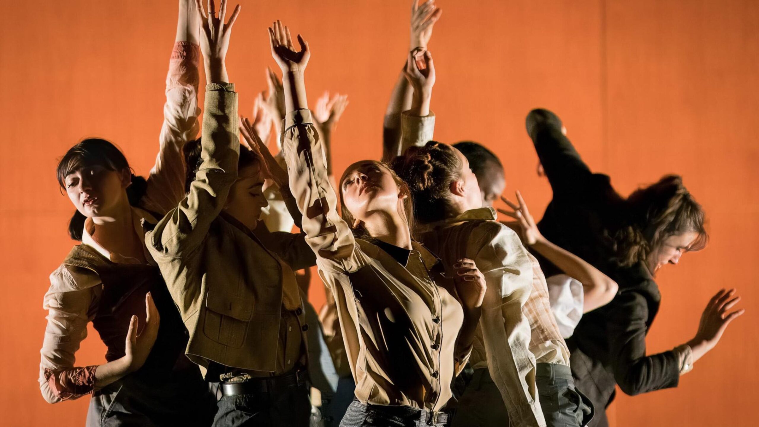 A group of dancers extending arms upward