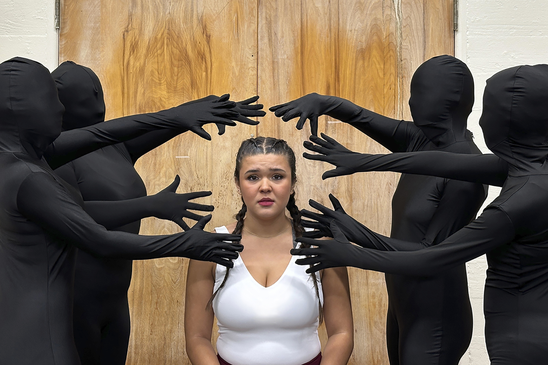 Four shrouded people surround a worried young woman.