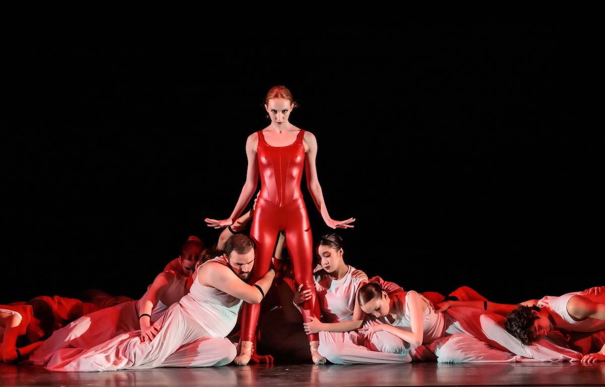 Female dancer standing on stage with dancers at her feet