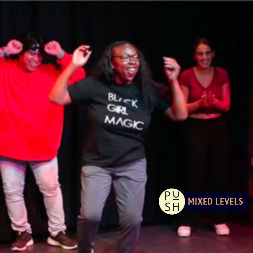 One dancer in the foreground is pictured grooving with her arms up, wearing a shirt that reads 