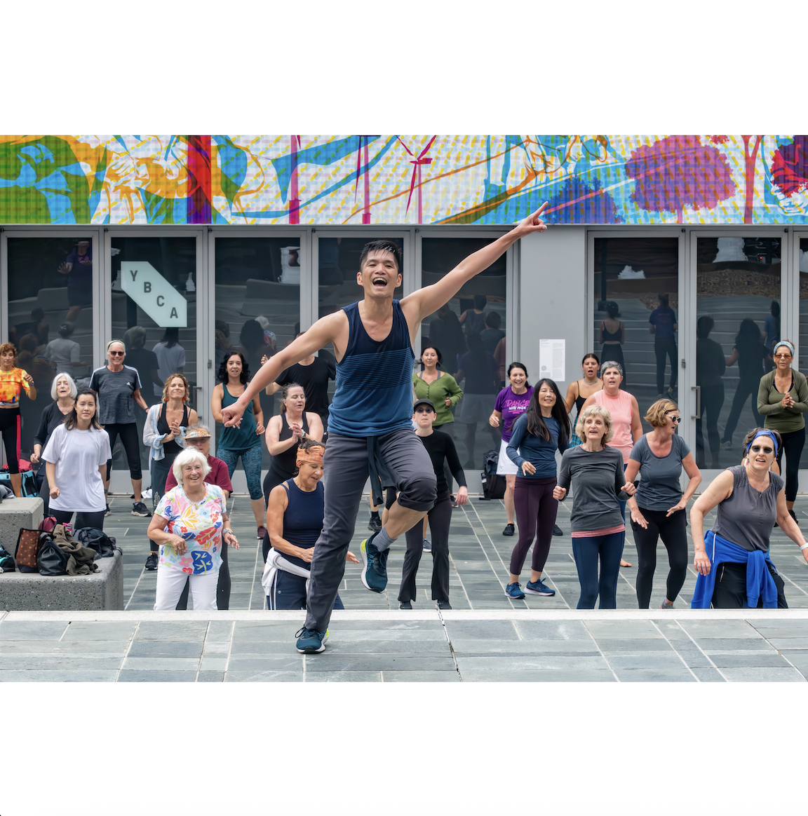 A diverse group of people dancing in a town square enjoying the outdoors and connecting with each other.