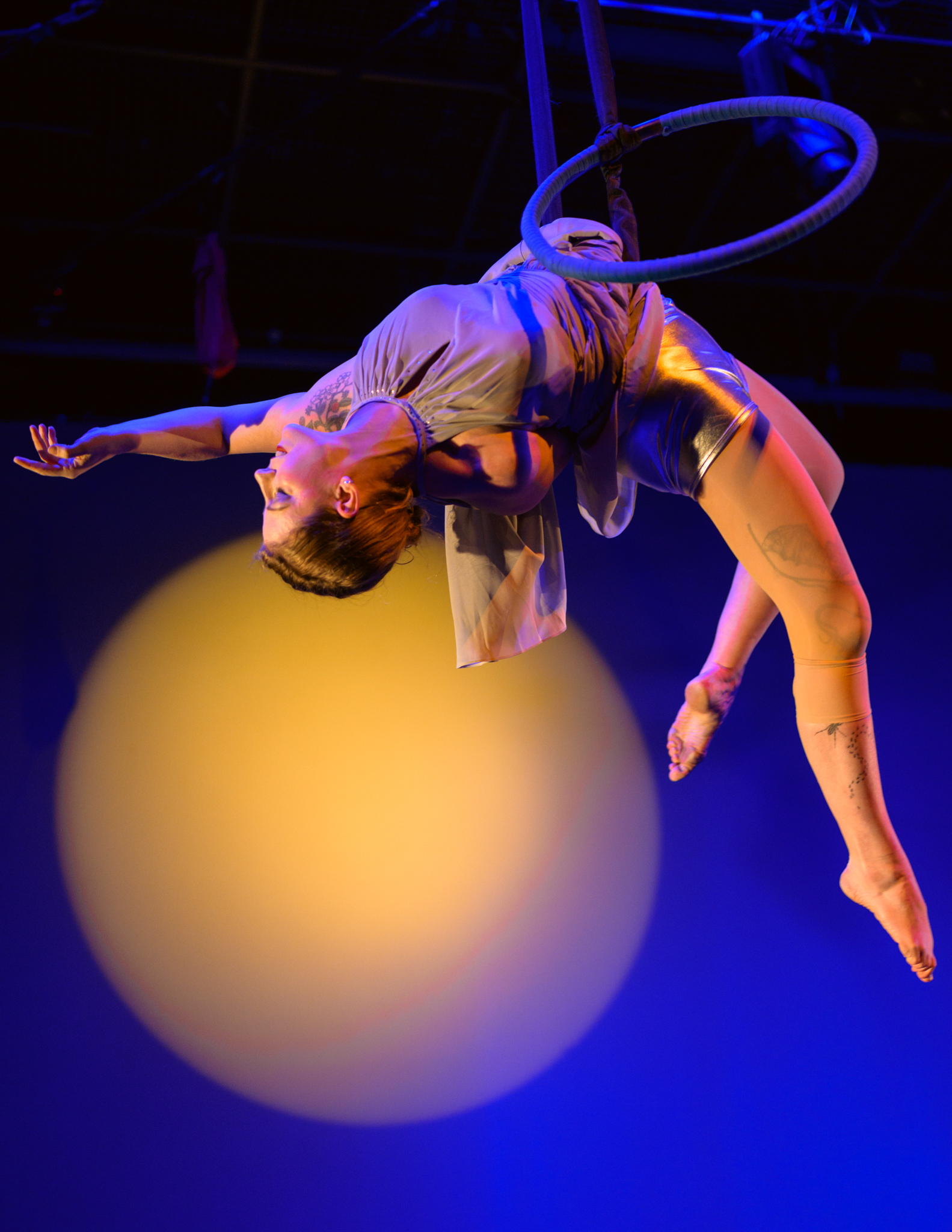 Aerial dancer does a backbend over the moon